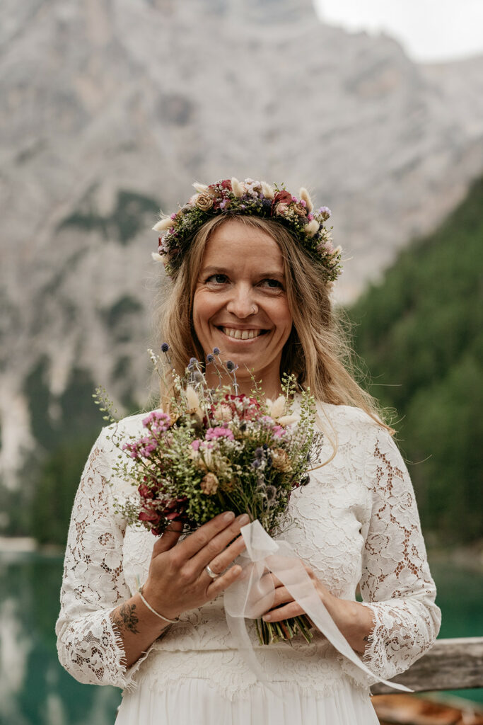 Smiling bride with floral crown and bouquet outdoors.