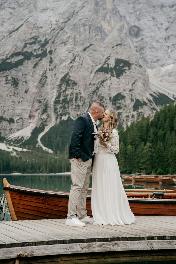 Couple kissing on dock by mountain lake.