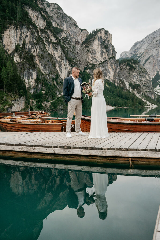 Couple exchanging vows on dock by lake.