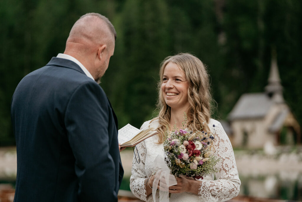 Couple exchanging vows outdoors by a small chapel.