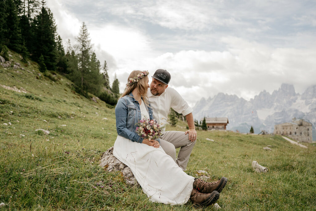 Couple sitting in mountain meadow, embracing romantically.