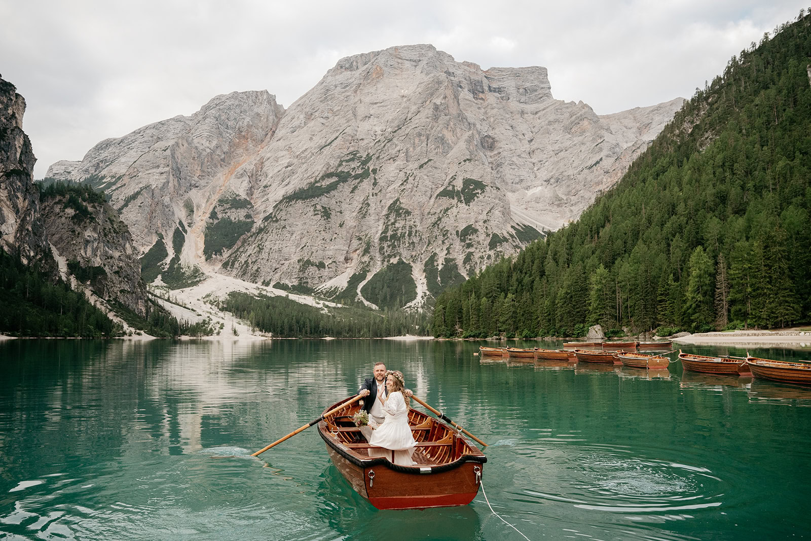 Couple in boat on turquoise mountain lake.