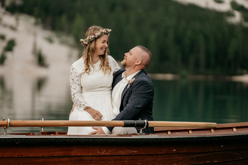 Couple smiling in a boat on a lake.