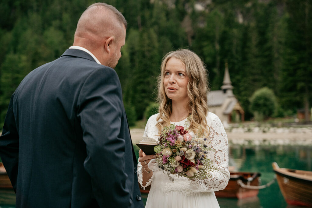Bride and groom exchange vows by a lake.