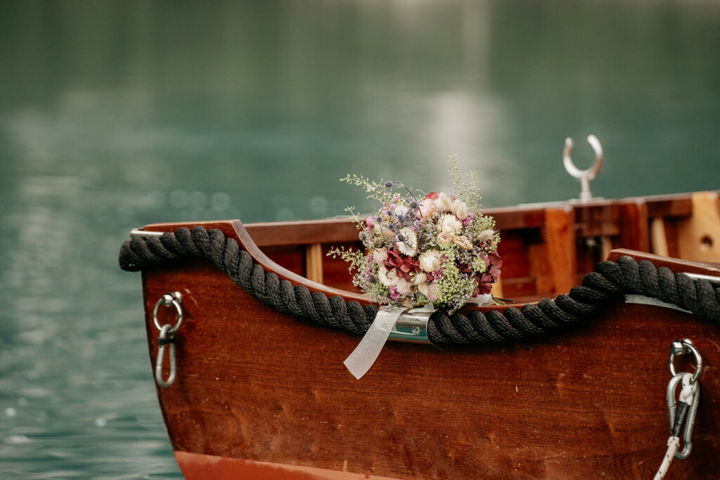 Flower bouquet on wooden boat by lake.