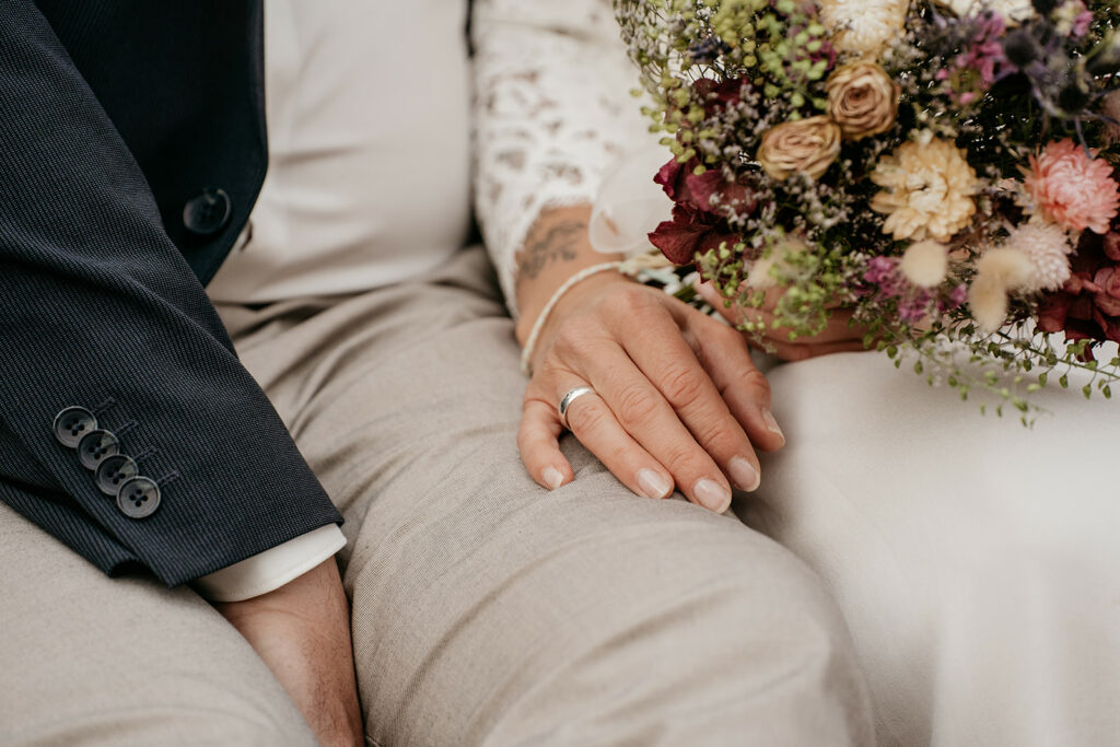 Close-up of couple's hands and bridal bouquet.
