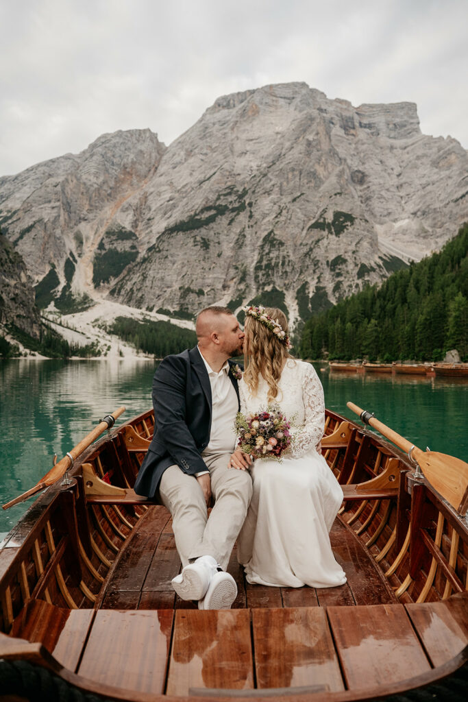 Couple kissing on boat in scenic mountain lake.