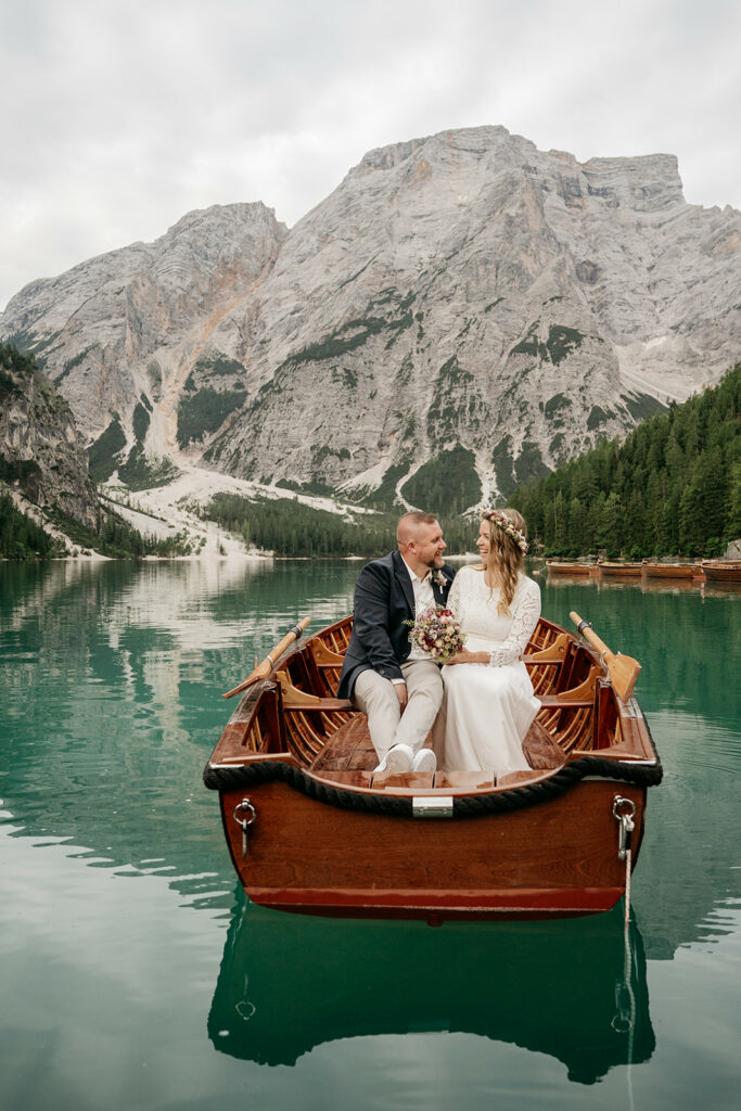 Couple in boat, scenic mountain backdrop.