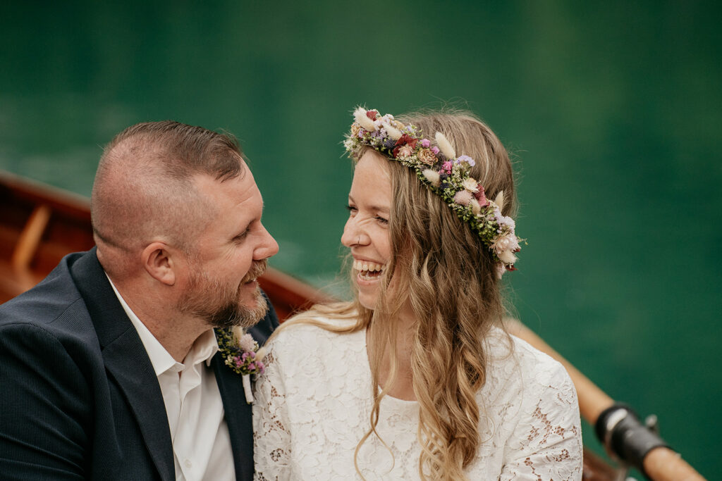 Smiling couple in a boat with floral headpiece.