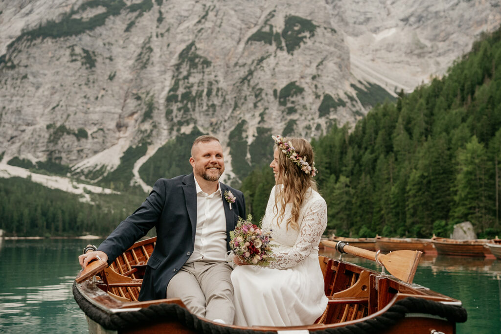 Couple smiling in rowboat with mountain backdrop.