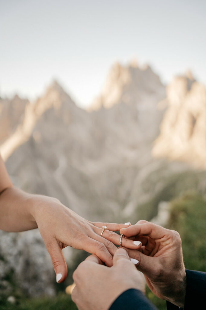 Couple exchanging rings in scenic mountain setting.