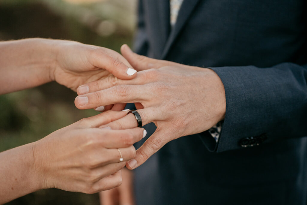 Hands exchanging wedding rings at ceremony.