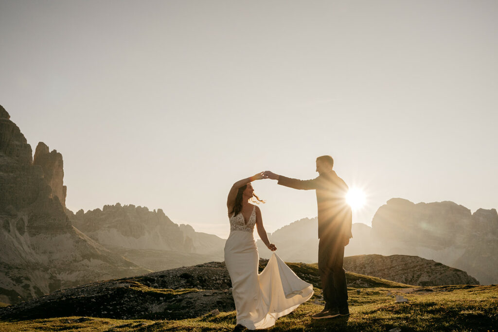 Couple dancing at sunset in mountainous landscape.