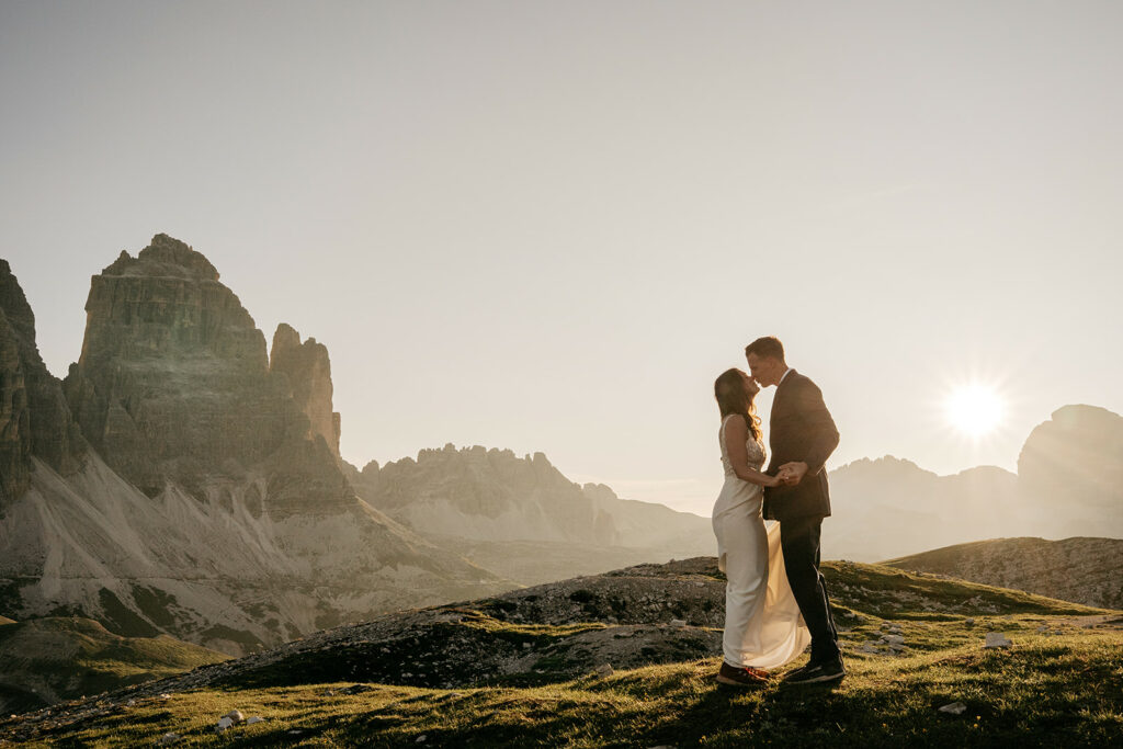 Couple embraces at sunset in mountainous landscape.