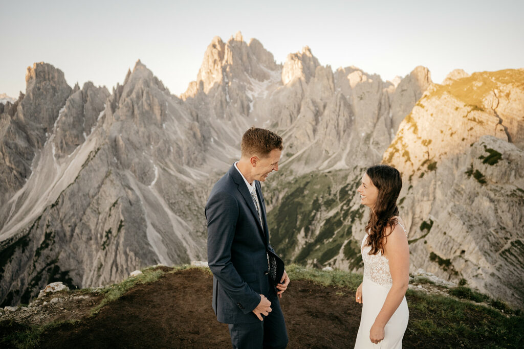 Couple smiling on mountain cliff during sunset