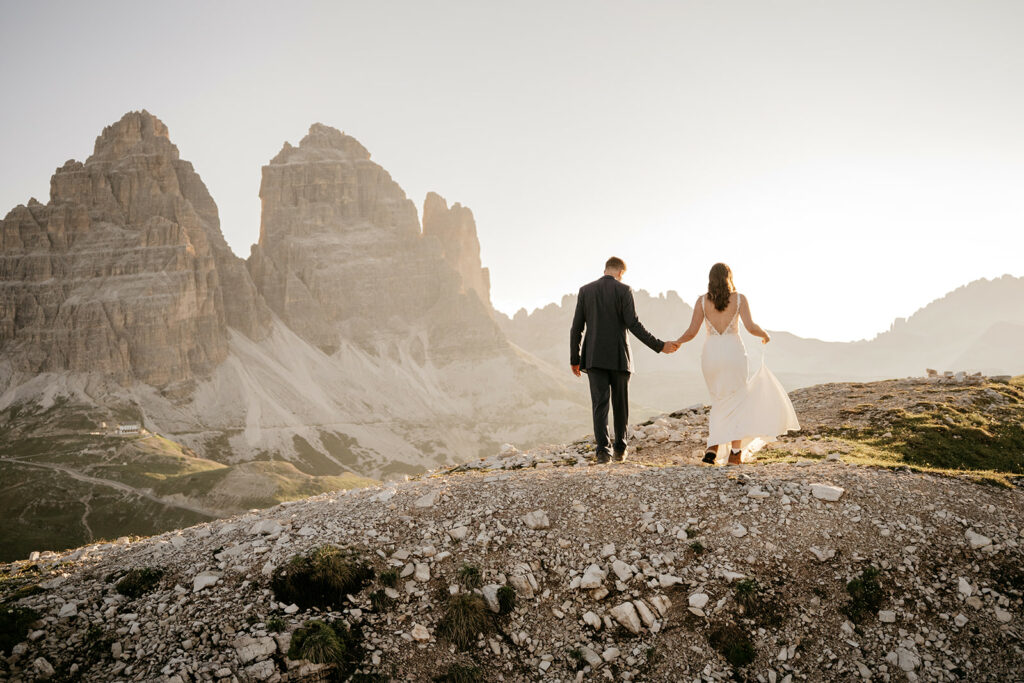 Couple holding hands, mountains in background, sunset.