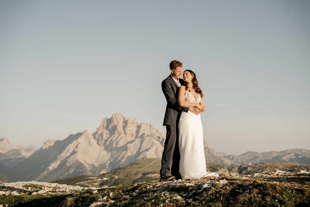 Couple embracing on mountain with scenic view.