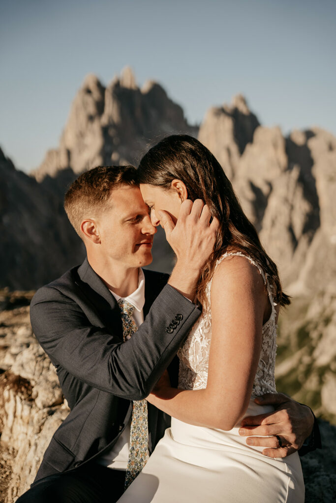 Couple embracing outside with mountains in background.