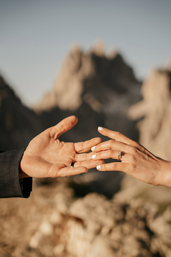 Hands reaching towards each other outdoors.