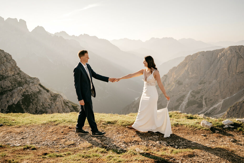 Bride and groom on mountain landscape at sunset.