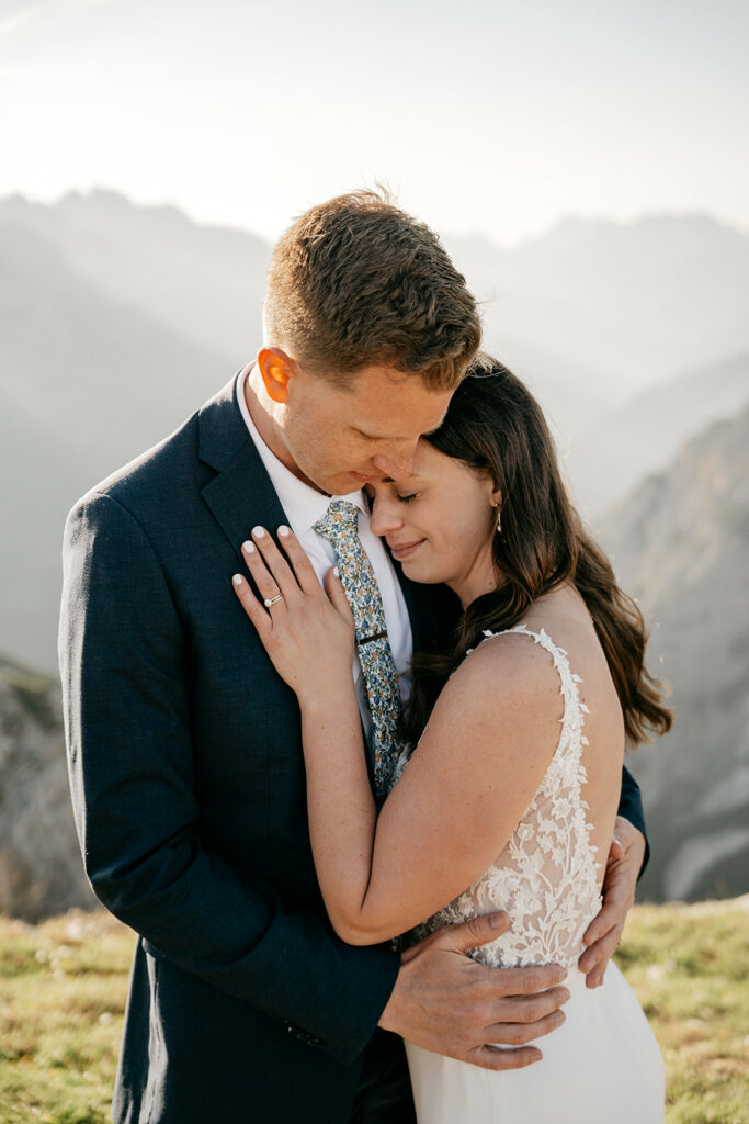 Couple embracing in mountain setting, wedding attire.
