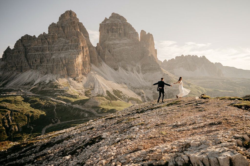Couple holding hands near mountain landscape.