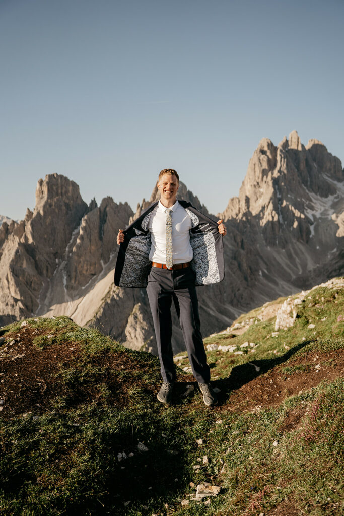 Man in suit smiling in mountain landscape.
