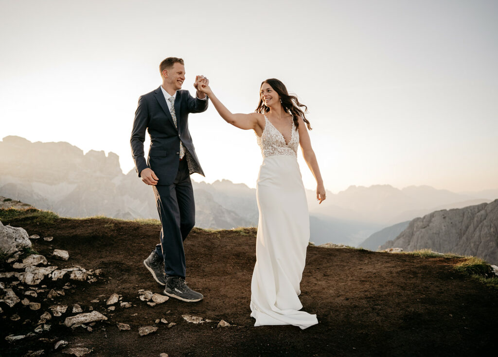 Couple dancing during mountain sunset in wedding attire.