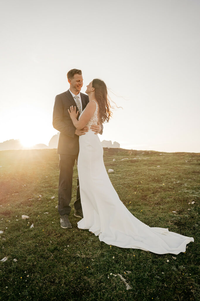 Couple embracing at sunset in wedding attire.