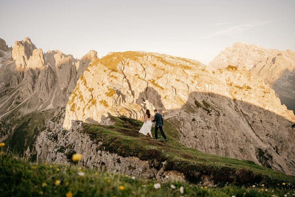 Couple walking on mountain ridge at sunset.