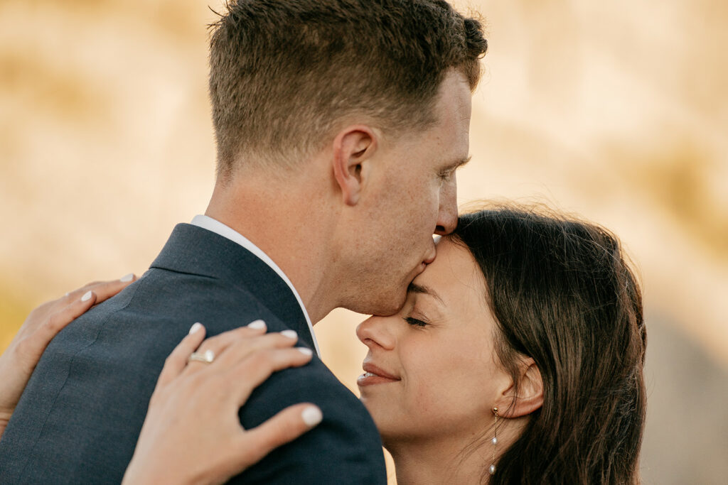 Man kissing woman's forehead, embracing lovingly.