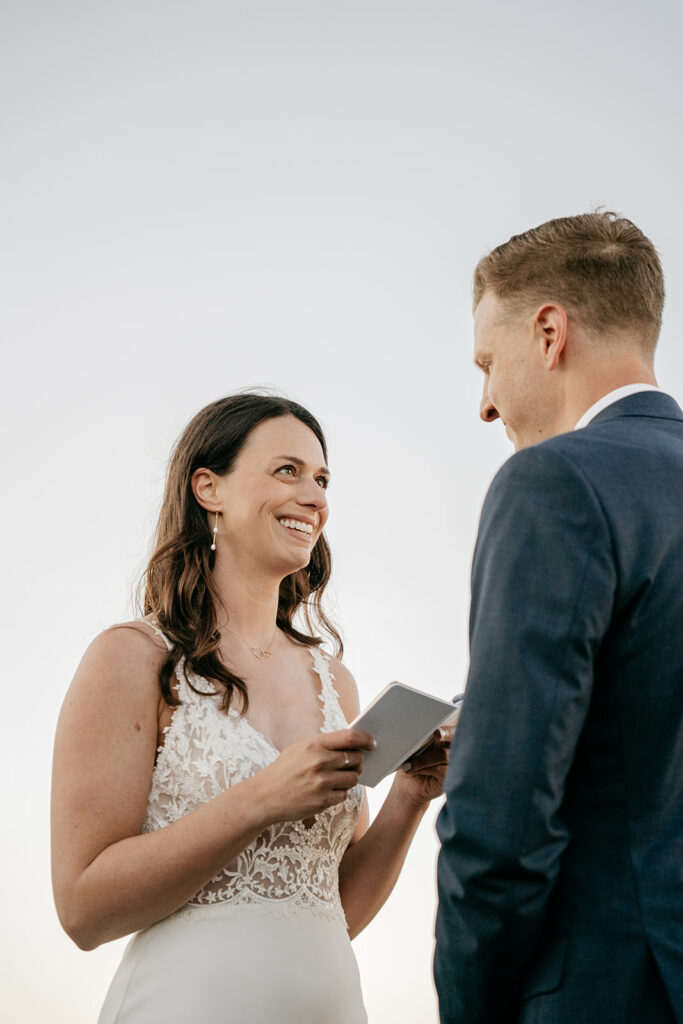 Bride reading vows to groom outdoors.