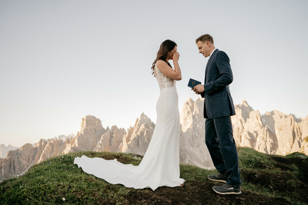 Couple eloping in mountains, exchanging vows outdoors.