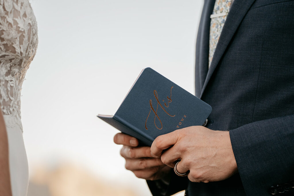 Groom holding a vows book during wedding ceremony.