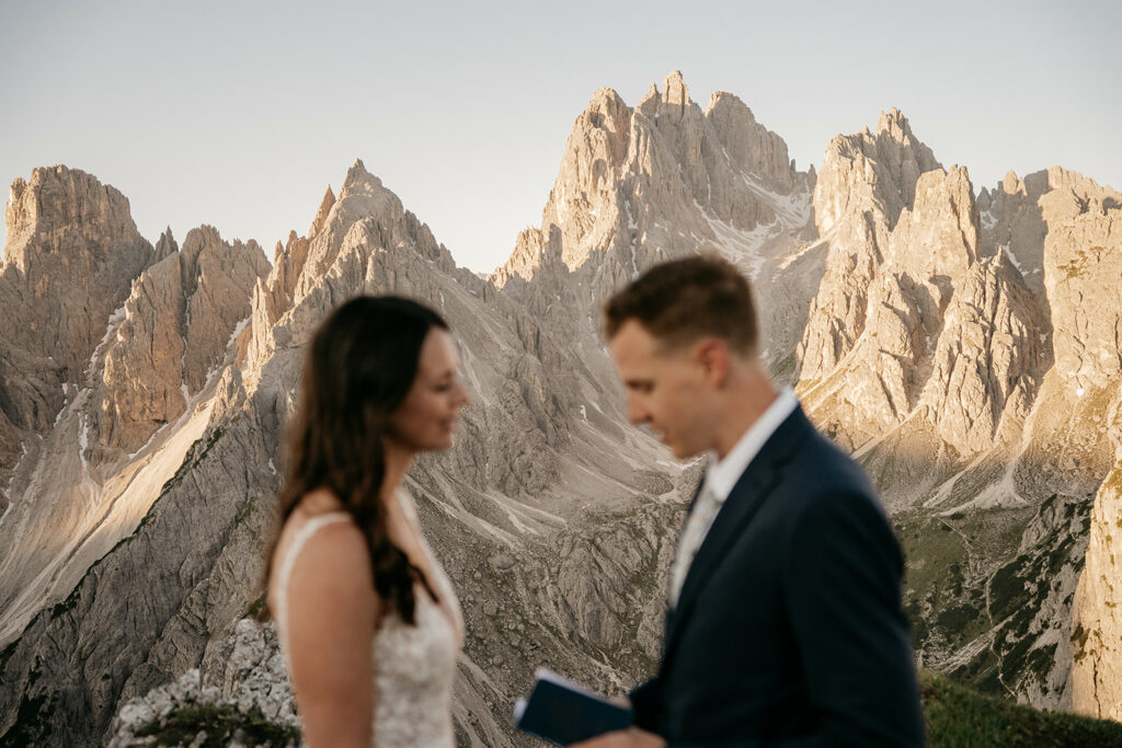 Couple in wedding attire with mountain backdrop.