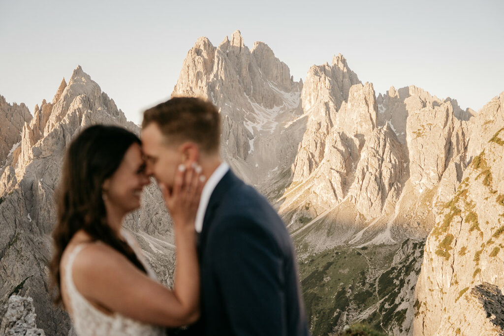 Couple embraces with mountains in the background.