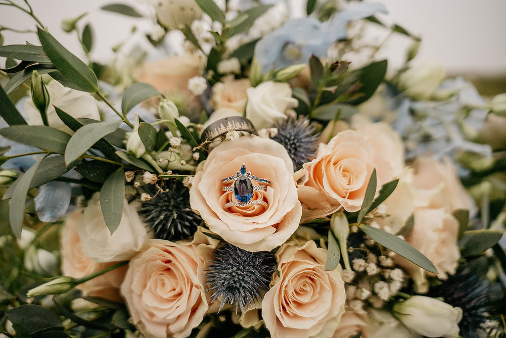 Engagement ring on peach roses in floral arrangement.