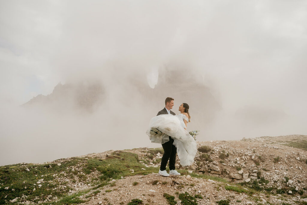 Bride and groom on mountain with misty background.
