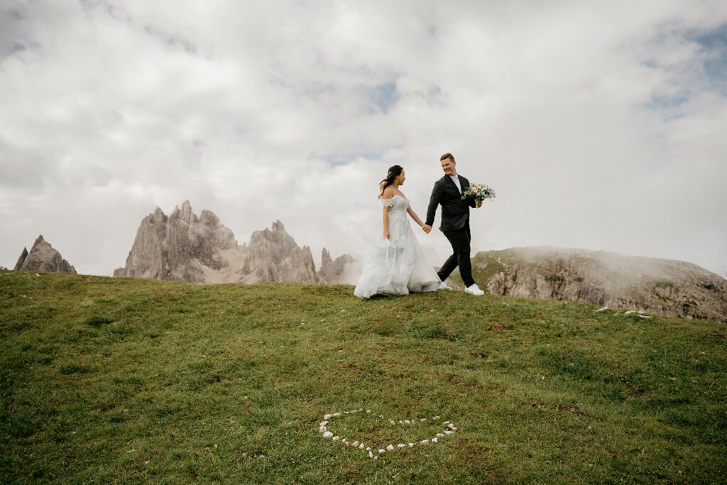 Bride and groom walking on mountain meadow
