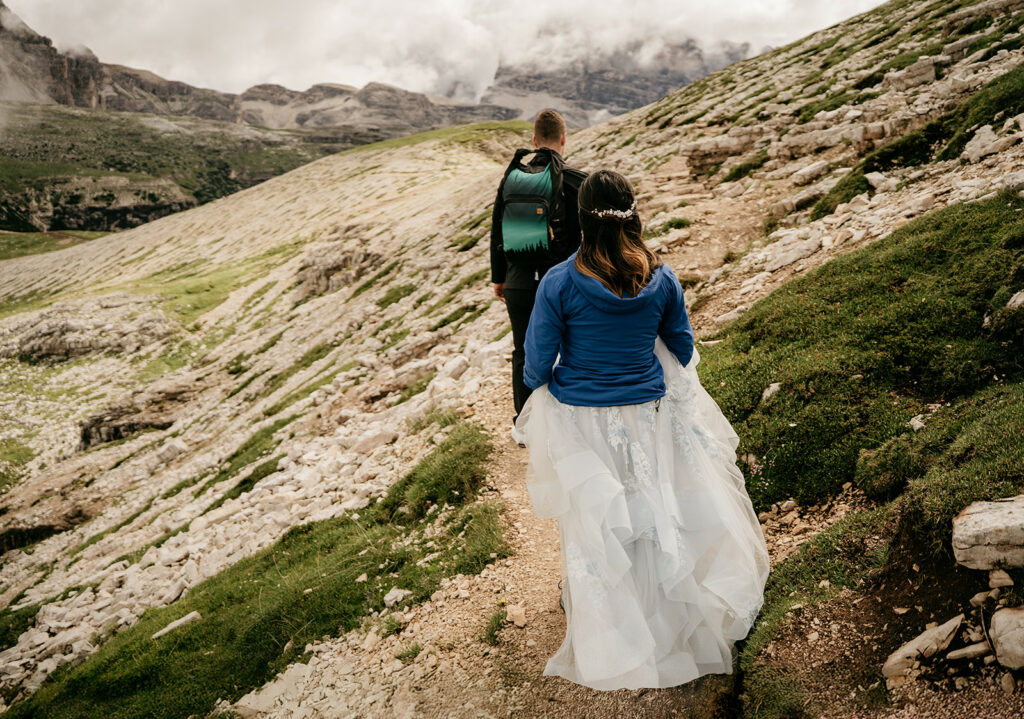 Hikers on mountain trail with cloudy sky.