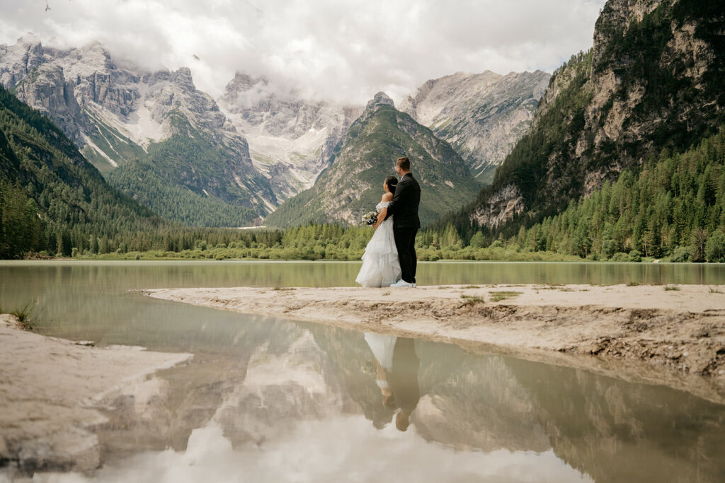 Couple embracing by mountain lake with reflection