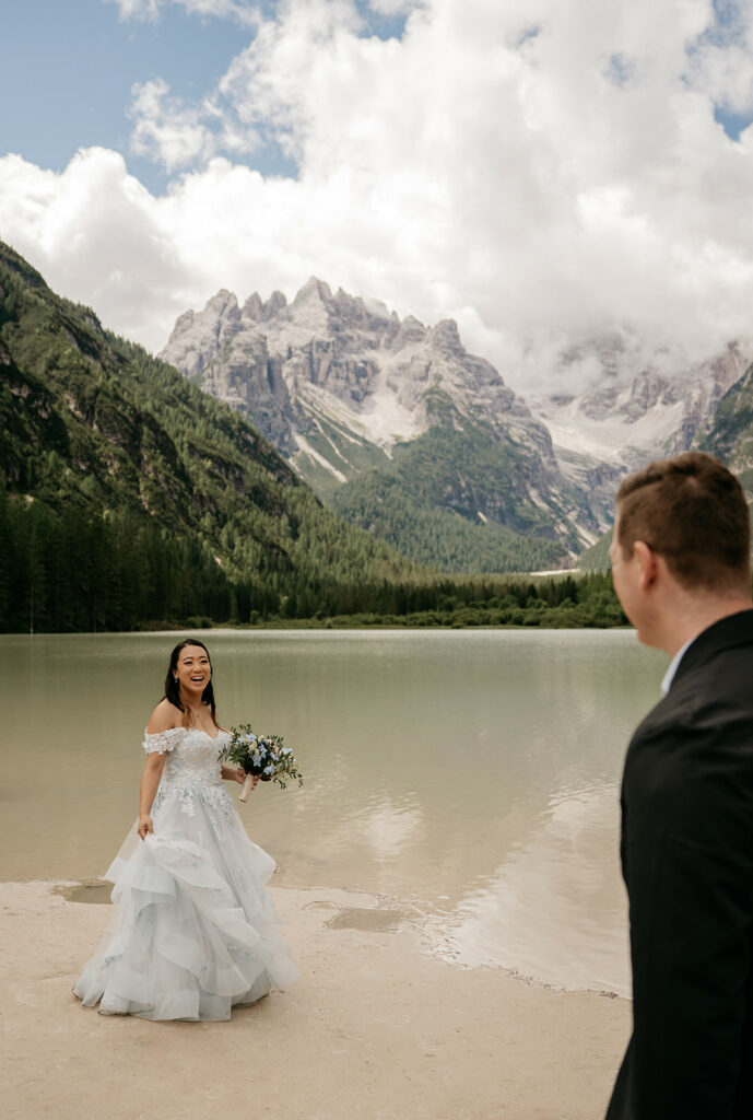 Bride and groom by mountain lake scenery.