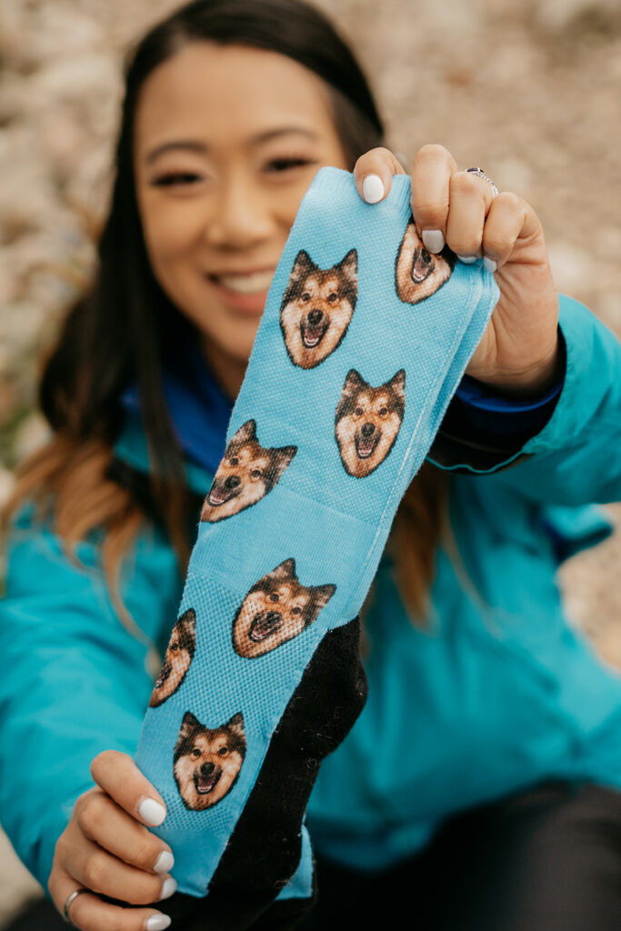 Person holding dog-themed socks, smiling.