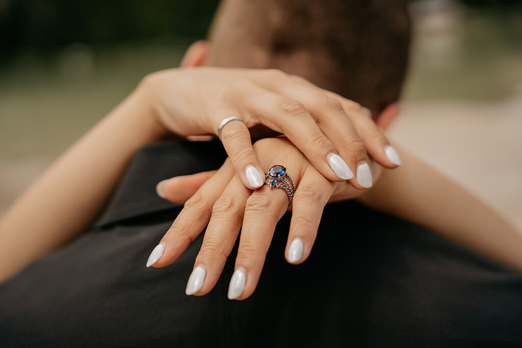 Hands with diamond ring embracing someone's neck.