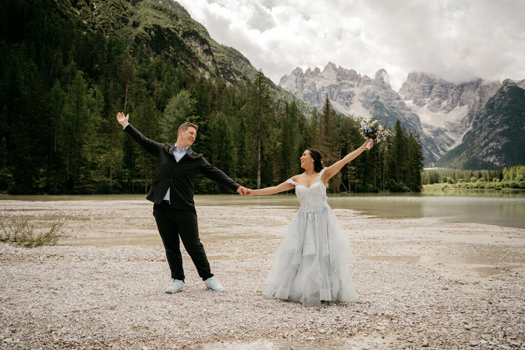 Couple celebrating wedding by mountain lake.