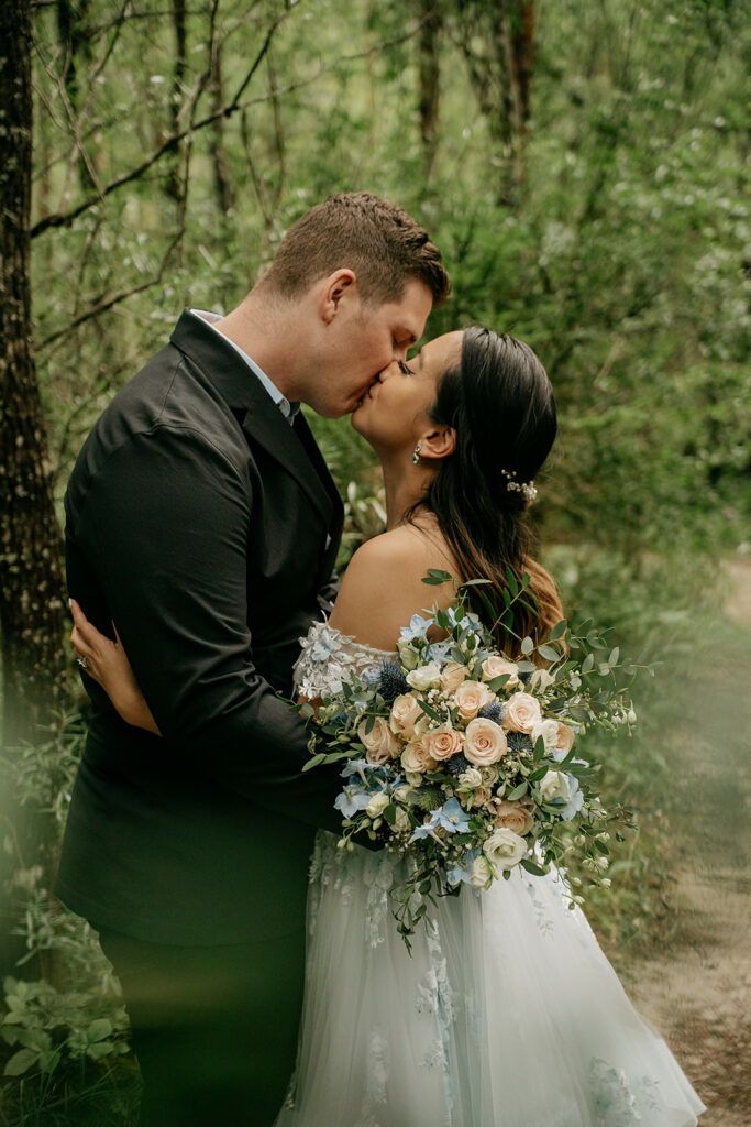 Bride and groom kissing in forest.