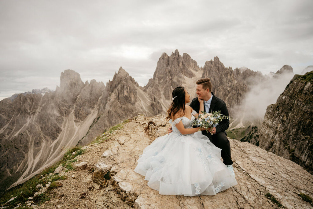 Couple embraces on mountain with stunning view.