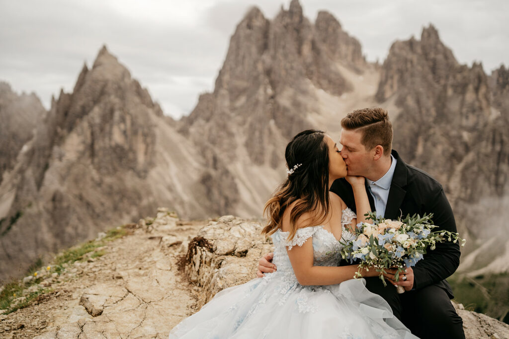 Couple kissing on mountain with bouquet