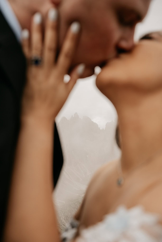 Couple kissing in a scenic mountain setting.
