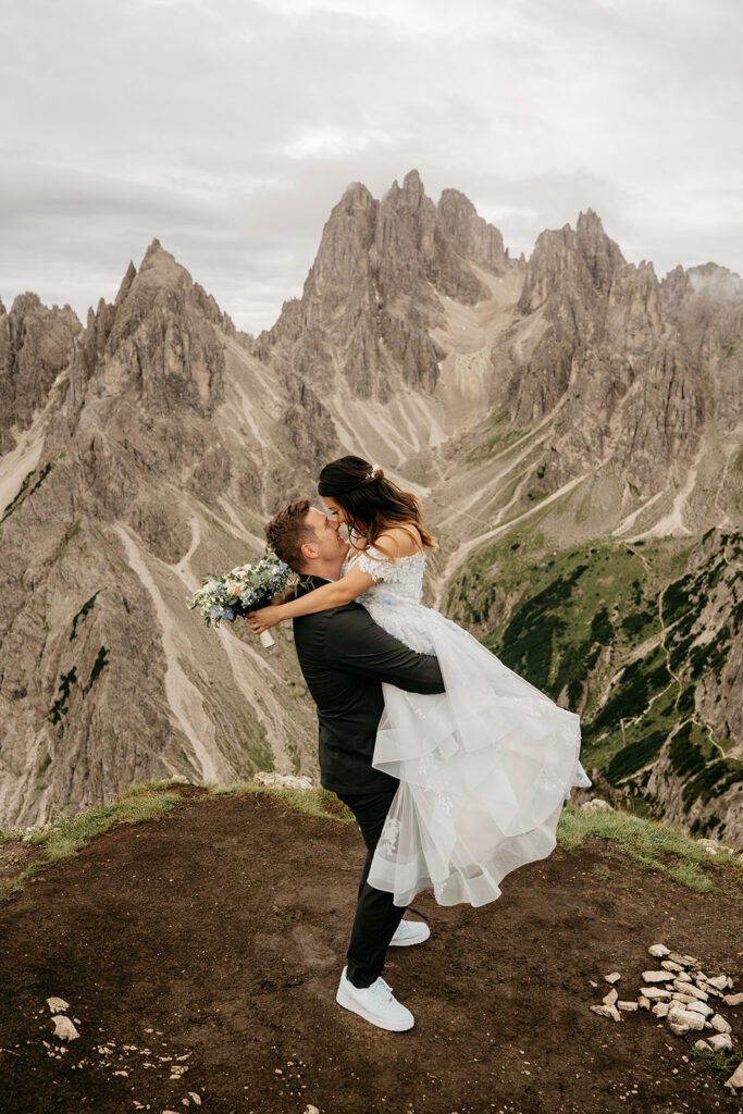 Couple embracing on mountain, scenic backdrop.